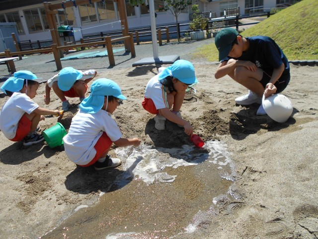 こども園の外でみんなで砂遊び